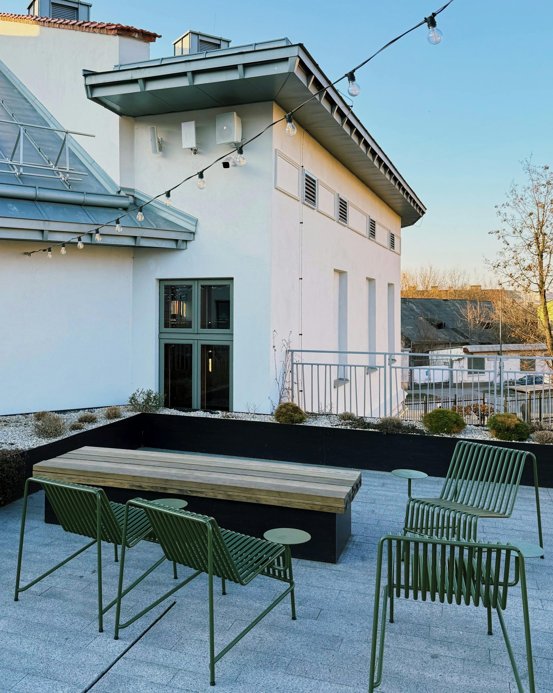 Élégante terrasse extérieure sur le toit avec chaises en métal vert et table en bois.